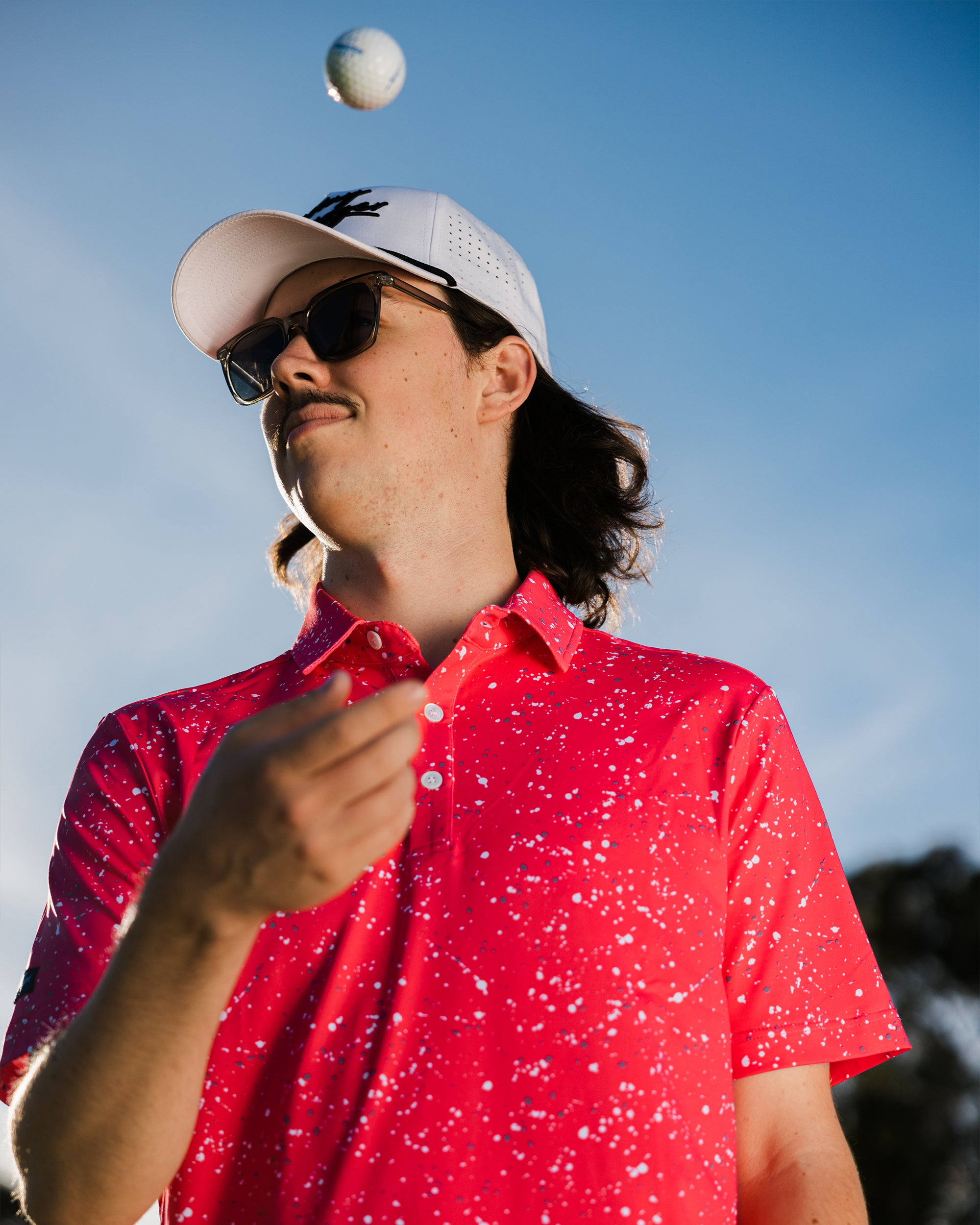 Gnarly mens golf polo. Man throwing golf ball in the air